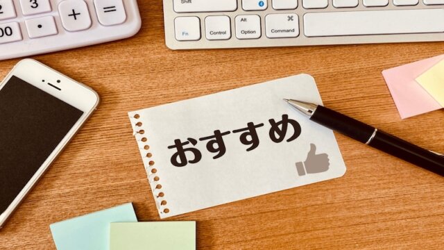 机の上にキーボードとスマートフォン、筆記用具が置かれている