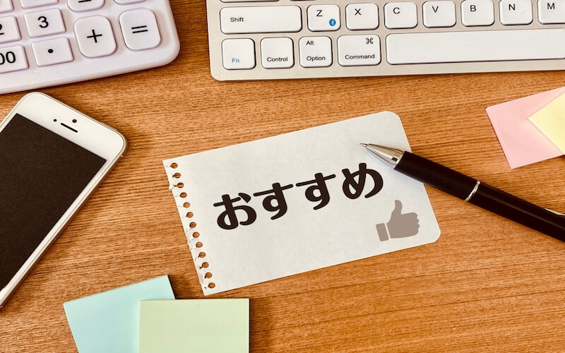 机の上にキーボードとスマートフォン、筆記用具が置かれている